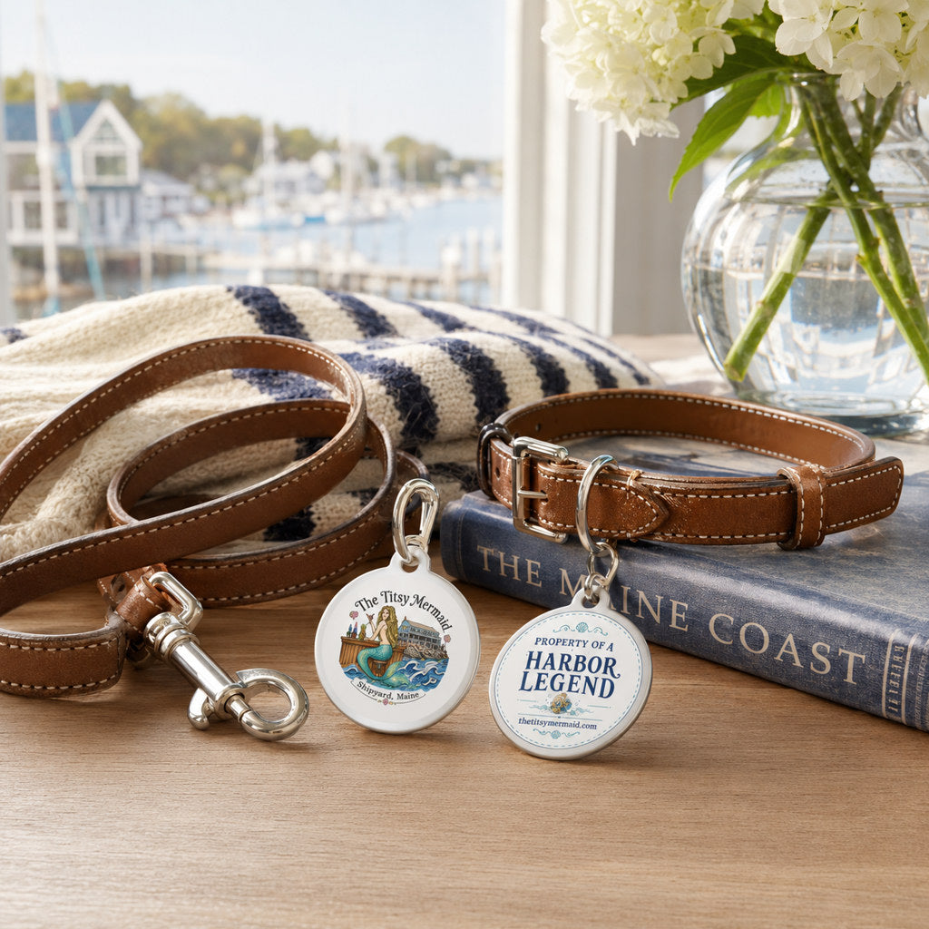 The Titsy Mermaid Harbor Legend Pet Tag flat lay with leather collar and coastal Maine props